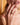 Close-up of a woman's hand with gold rings, wearing a red top against a blurred background.