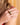Close-up of a hand wearing a gold ring with a pearl on a blurred background